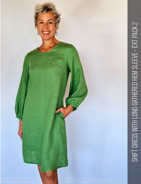 Woman wearing a green linen shift dress with long gathered hem sleeve against a plain background